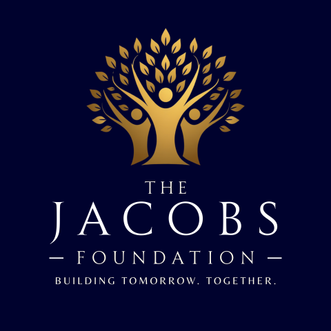 Primary logo is set against a deep navy blue background. The central icon is a golden stylized family tree . The branches grow upward and outward in a structed, geometric pattern, ending in small, defined leaves to create a rounded canopy. Directly underneath the tree (at its roots) is the prominent word "Jacobs" and below it, the word "Foundation" is written smaller. And below that "Building Tomorrow. Together." Wording is white in color.