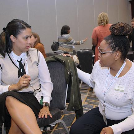 A presenter and participant conversing during a session at the conference.